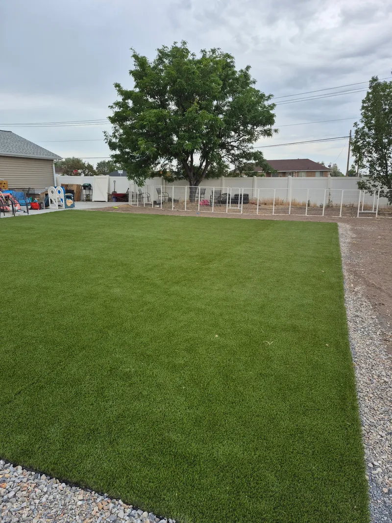 Finished artificial turf lawn cut and seamed to meet a gravel edge across a Utah backyard