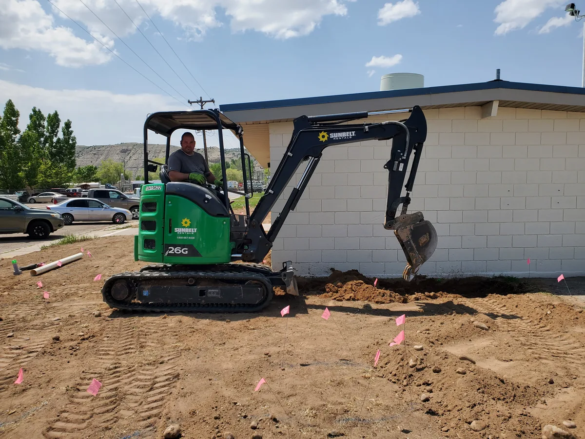 Carey Cordova, owner of SLC Landscaping & Dumpsters, running an excavator at a Salt Lake County job site