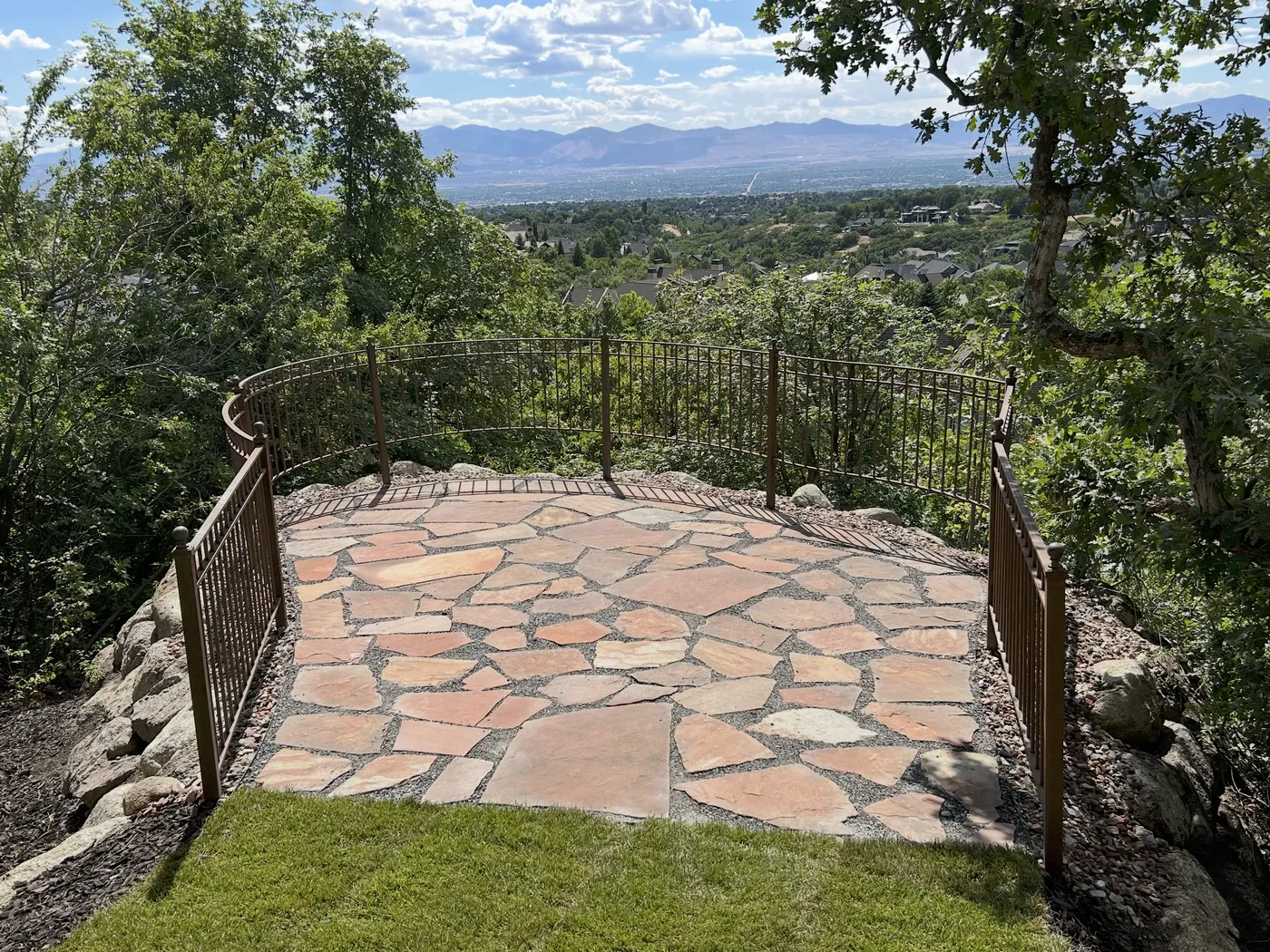 Finished flagstone patio overlook framed by a wrought-iron railing with a sweeping Salt Lake Valley view beyond